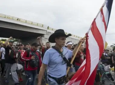 A migrant carries a U.S. flag. Isabel Mateos/AP