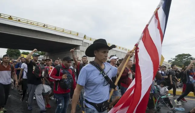 A migrant carries a U.S. flag. Isabel Mateos/AP