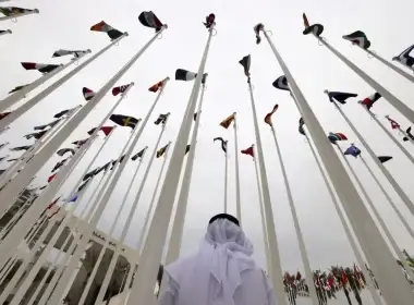 An Emirati visitor stands beneath the waving flags of countries participating in Expo 2020 in the Gulf Emirate of Dubai on October 6, 2021. Karim Sahib/AFP