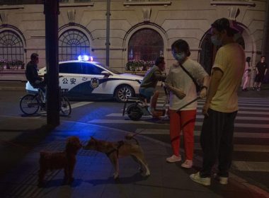 A police car patrols the street as residents gather nearby, Tuesday, May 31, 2022, in Shanghai. (AP Photo/Ng Han Guan)