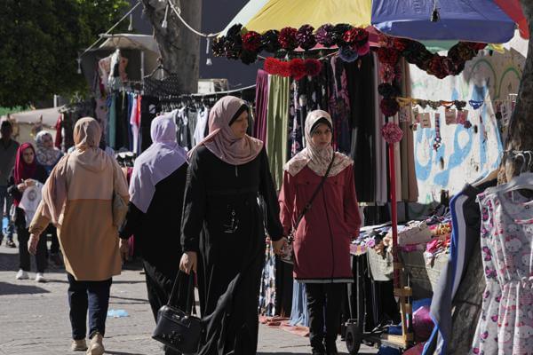 Women shop for clothes on the main road of an outdoor clothes market in Gaza City, Monday, July 25, 2022. AP