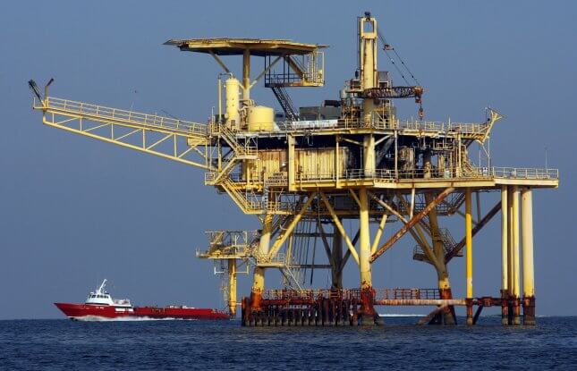 A supply boat, lower left, passes an oil production platform in the Gulf of Mexico. File Photo by A.J. Sisco/UPI