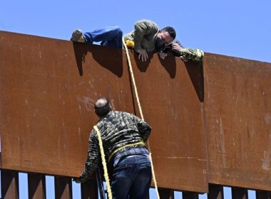 People use a ladder to scale the border fence at the US/Mexico border in Tecate, Mexico, Thursday, April 21, 2022. The men used the ropes to lower themselves down on the United States side. Denis Poroy | AP
