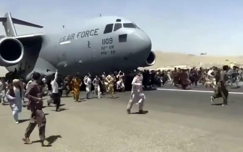People run alongside a U.S. Air Force C-17 transport plane as it moves down a runway of the Kabul airport in Afghanistan on Monday.Verified UGC via AP