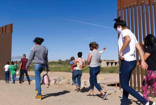 In this Tuesday, June 8, 2021, photo, a group of Brazilian migrants make their way around a gap in the U.S.-Mexico border in Yuma, Ariz., seeking asylum in the United States after crossing over from Mexico. Eugene Garcia / AP