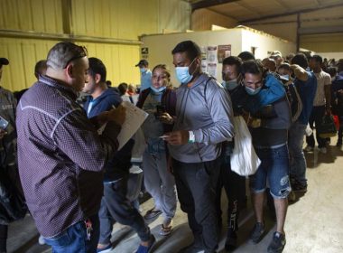 People line up for a commercial bus that will take them to the San Antonio airport at a warehouse run by the Mission: Border Hope nonprofit group run by the United Methodist Church in Eagle Pass, Texas, May 23, 2022. AP