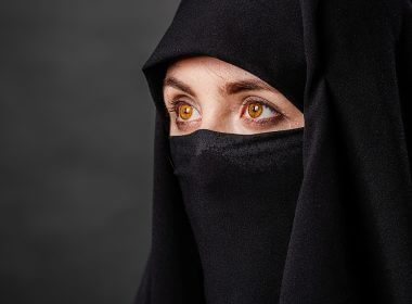 Portrait of young, adult Afghani woman in black burqa with hidden face | Shutterstock