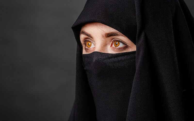 Portrait of young, adult Afghani woman in black burqa with hidden face | Shutterstock