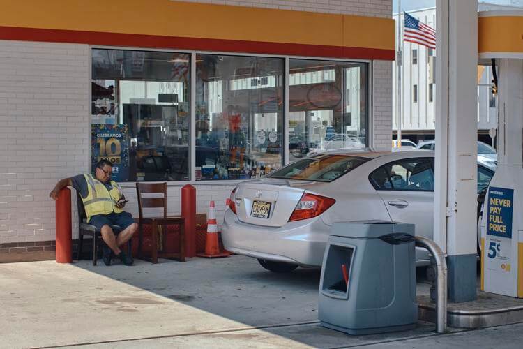 An employee checks his phone as he waits to serve a customer at a gas station on Wednesday in Jersey City, New Jersey. Consumers are feeling the pinch of inflation despite falling gas prices. Andres Kudacki / AP photo
