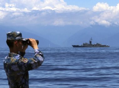 A People's Liberation Army service member looks through binoculars during military exercises as Taiwan's frigate Lan Yang is seen at sea on Aug. 5, 2022. (Lin Jian/Xinhua via AP, File)