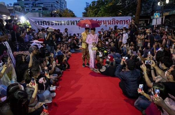 Pro-democracy protesters perform on a mock "red carpet" fashion show billed as a sort of counterpoint to a fashion show being held by one of the monarchy's princesses nearby in Bangkok, Thailand on Oct. 29, 2020. AP