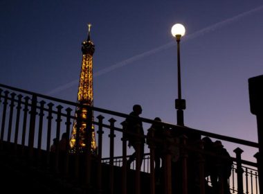 People walk on a bridge next to the Eiffel Tower in Paris, Wednesday Feb. 9, 2022. AP