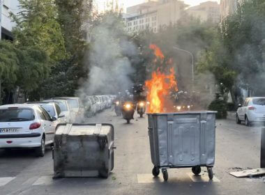 In this Tuesday, Sept. 20, 2022, photo taken by an individual not employed by the Associated Press and obtained by the AP outside Iran, a trash bin is burning as anti-riot police arrive during a protest over the death of a young woman who had been detained for violating the country's conservative dress code, in downtown Tehran, Iran. AP