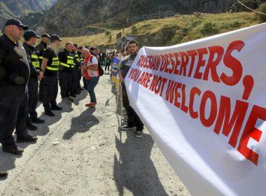 Georgian police form a line in front of activists holding an anti-Russian banner during an action organized by political party Droa near the border crossing at Verkhny Lars between Georgia and Russia in Georgia, Wednesday, Sept. 28, 2022. AP