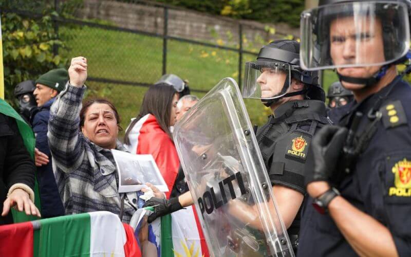 Policemen stand guard as demonstrators gather outside Iran's embassy in Oslo, Norway, Thursday, Sept. 29, 2022. AP