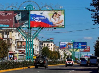 Vehicles drive past advertising boards, including panels displaying pro-Russian slogans, in a street in the course of Russia-Ukraine conflict in Luhansk, Ukraine September 20, 2022. REUTERS/Alexander Ermochenko