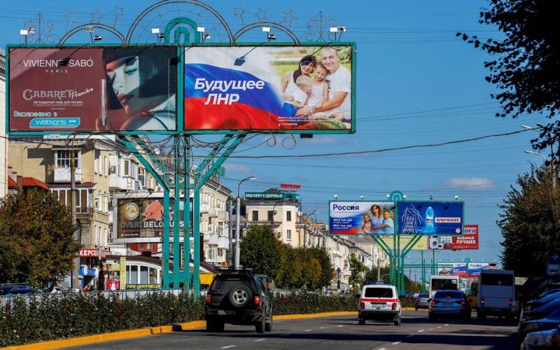 Vehicles drive past advertising boards, including panels displaying pro-Russian slogans, in a street in the course of Russia-Ukraine conflict in Luhansk, Ukraine September 20, 2022. REUTERS/Alexander Ermochenko