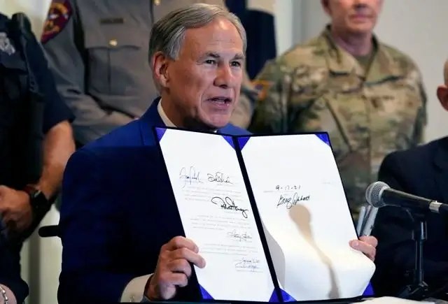 Texas Gov Greg Abbott displays a bill he signed into law that provides additional funding for security at the U.S.-Mexico border Friday, Sept. 17, 2021, in Fort Worth. AP