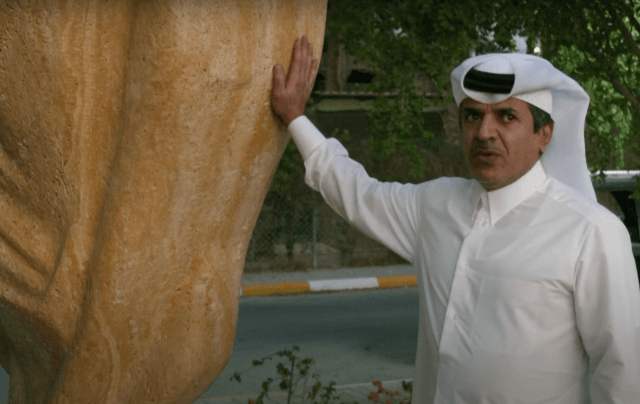 Qatari Sheikh Hamad Al Suwaidi with a three-meter high stone replica of the World Cup trophy he installed outside his home in Doha. (Photo: Screenshot)