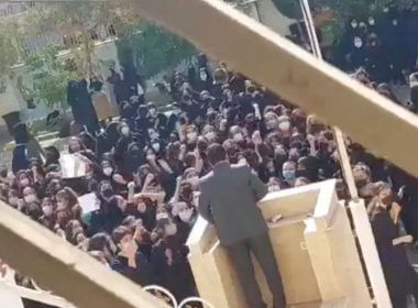 Female protesters react and chant towards a man standing at a podium in Shiraz, Fars province, Iran October 4, 2022 in this still image from a video obtained by REUTERS