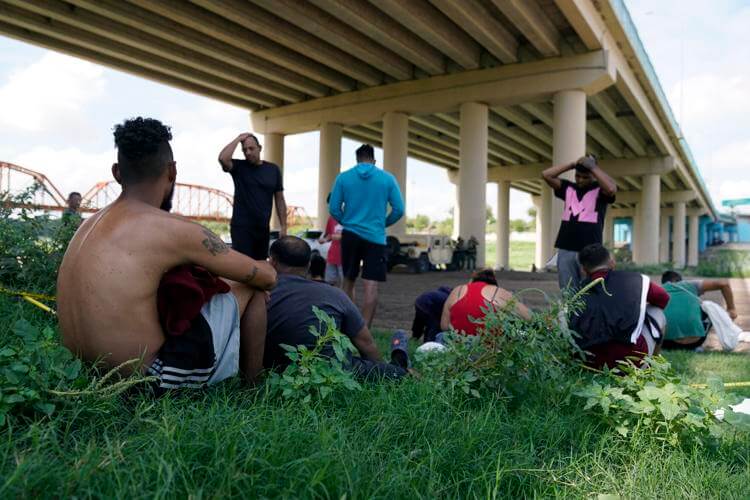 Migrants wait to be processed by the Border Patrol after illegally crossing the Rio Grande river from Mexico into the U.S. at Eagle Pass, Texas, Friday, Aug. 26, 2022. Eric Gay