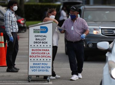 Poll workers at the Miami-Dade County Elections Department deposit returned mail-in ballots into an official ballot drop box on primary election day on Aug. 18 in Doral, Fla. Image credit: Joe Raedle