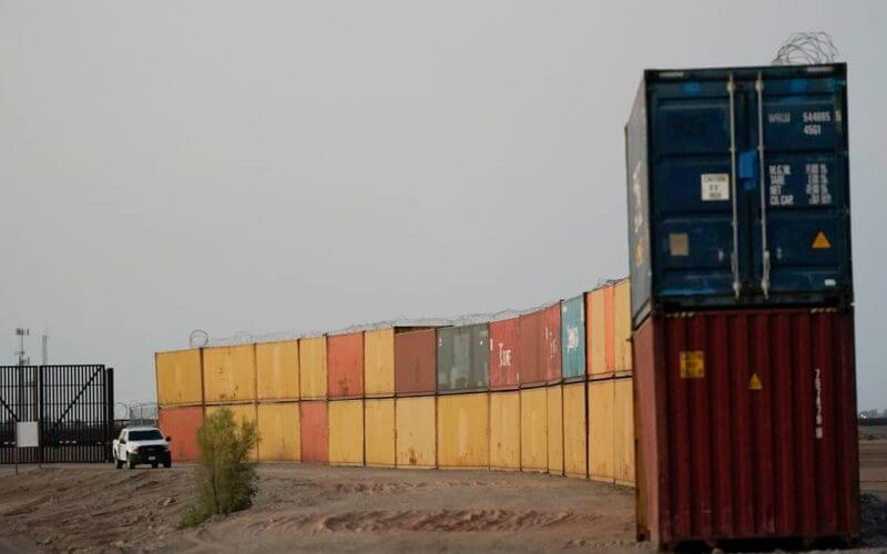 Border Patrol agents patrol along a line of shipping containers stacked near the border on Aug. 23, 2022, near Yuma, Ariz. AP