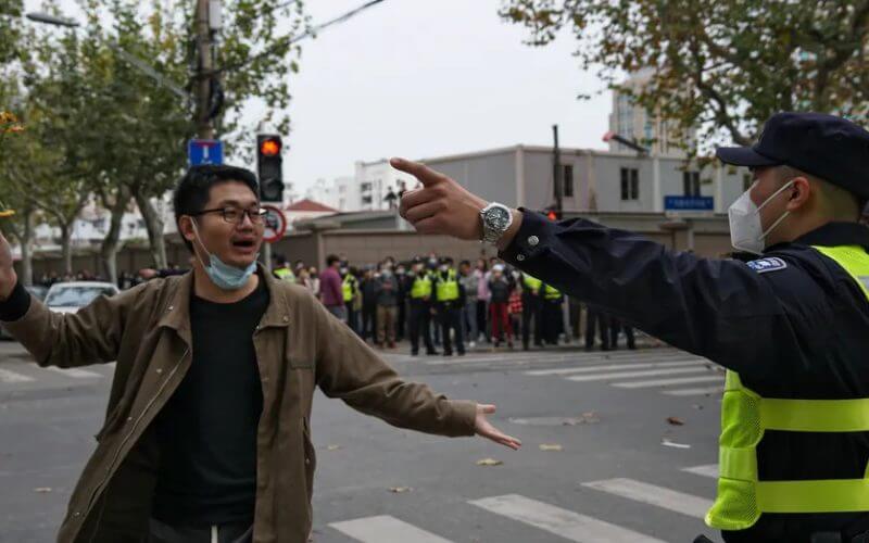 A protester holding flowers is confronted by a policeman on a street in Shanghai, China, on Nov. 27, 2022. (AP Photo)