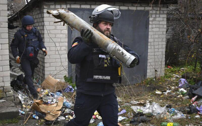 A Ukrainian sapper carries a part of a projectile during a demining operation in a residential area in Lyman, Donetsk region, Ukraine, Wednesday, Nov. 16, 2022. (AP Photo/Andriy Andriyenko)