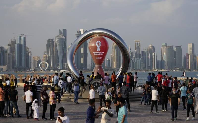 People gather around the official countdown clock showing remaining time until the kick-off of the World Cup 2022, in Doha, Qatar, Friday, Nov. 11, 2022. AP