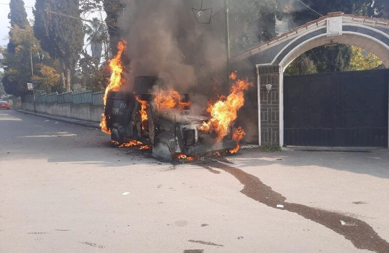 A police vehicle burns as Syrians take part in an anti-government protest in Sweida [Suwayda 24/via Reuters]