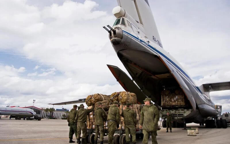 Russian air force personnel prepare to load cargo on board a Syrian Il-76 plane at Hemeimeem air base in Syria. AP