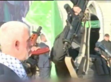 A masked member of Hamas holds up the supposed weapon of slain Israeli soldier Hadar Goldin, as the terror group's Gaza leader Yahya Sinwar looks on during a rally, December 14, 2022. (Video screenshot)