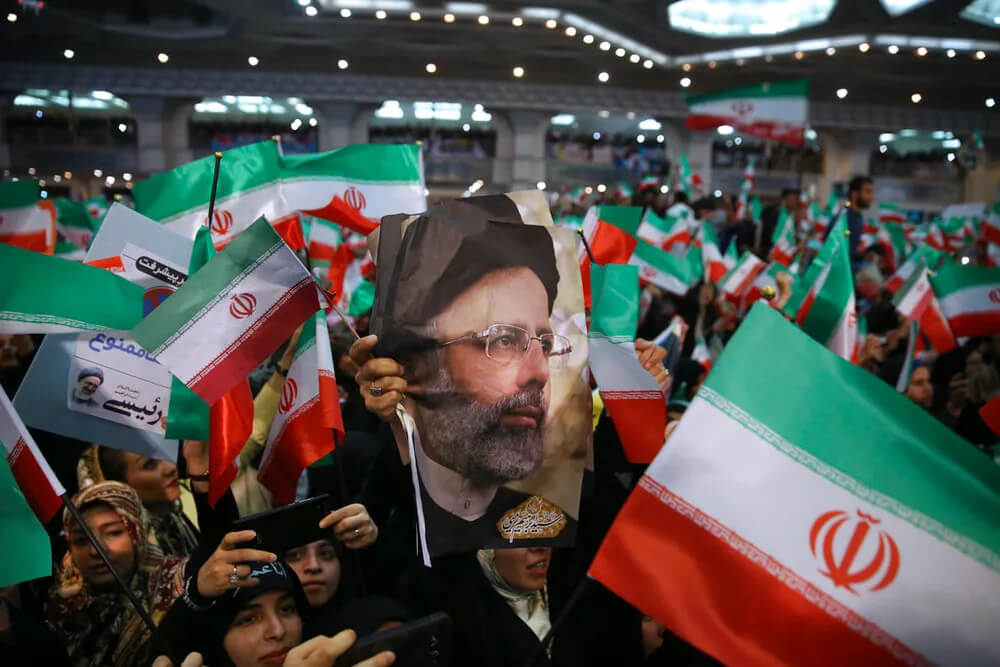 Supporters of hard-line cleric Ebrahim Raisi hold his photo and wave their country's flag in Tehran, Iran. AP