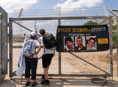 Israelis look towards the fence for the Erez border crossing on the Israel-Gaza border, next to a banner showing captive Israeli civilians Avera Mengistu (L) and late soldiers Oron Shaul (C) and Hadar Goldin. AP
