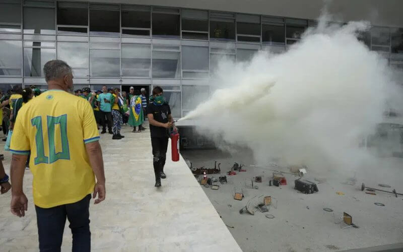 A protester, supporter of Brazil's former President Jair Bolsonaro, empties a fire extinguisher after protesters stormed Planalto Palace in Brasilia, Brazil, Sunday, Jan. 8, 2023. AP
