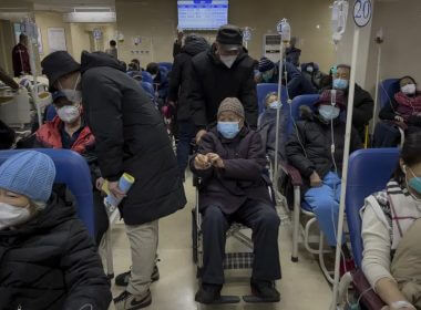 A man pushes an elderly woman past patients receiving intravenous drips in the emergency ward of a hospital, Tuesday, Jan. 3, 2023. AP