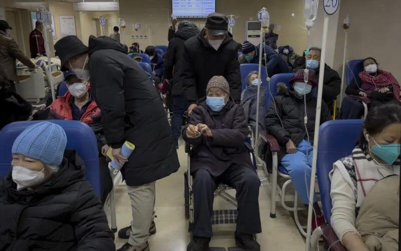 A man pushes an elderly woman past patients receiving intravenous drips in the emergency ward of a hospital, Tuesday, Jan. 3, 2023. AP