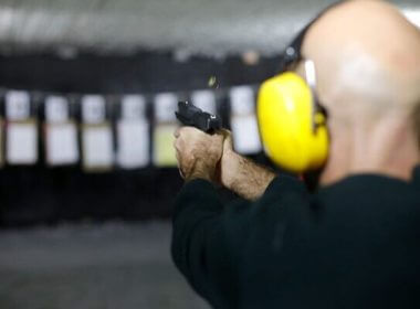 A man fires a pistol at an indoor shooting range during a qualification course in Katzrin in Golan Heights on January 31, 2023. (JALAA MAREY / AFP)
