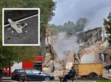A local resident sits outside a building destroyed by Russian forces using Iranian-made drones after an airstrike on Bila Tserkva, southwest of Kyiv, Ukraine, on October 5, 2022. SERGEI SUPINSKY/AFP; ARIS MESSINIS / AFP/GETTY IMAGES