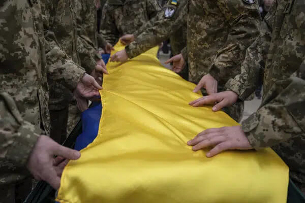 Ukrainian servicemen fold the national flag over the coffin of their comrade Andrii Neshodovskiy during the funeral ceremony in Kyiv, Ukraine, Saturday, March 25, 2023. (AP Photo/Evgeniy Maloletka)