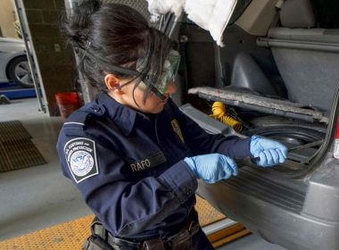 A U.S. Customs and Border Protection agent searches an automobile for contraband in the line to enter the United States at the San Ysidro Port of Entry in October 2019 in San Ysidro, Calif. / AFP via Getty Images