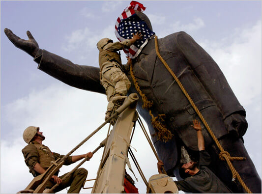 A marine covered a statue of Saddam Hussein with Tim McLaughlin’s American flag in Baghdad in 2003. (Photo: Jerome Delay/Associated Press)