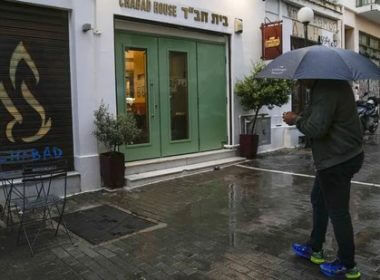 A man holding an umbrella stands in front of a Jewish restaurant that Greek officials believe was one of the targets of a planned terrorist attack, in central Athens. AP