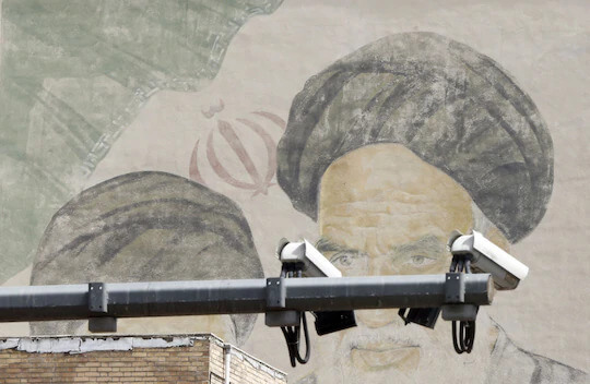 CCTV cameras are seen in front of an image of Iran’s late supreme leader, Ayatollah Ruhollah Khomeini, on a street in Tehran on April 10. (Abedin Taherkenareh/EPA-EFE/Shutterstock)