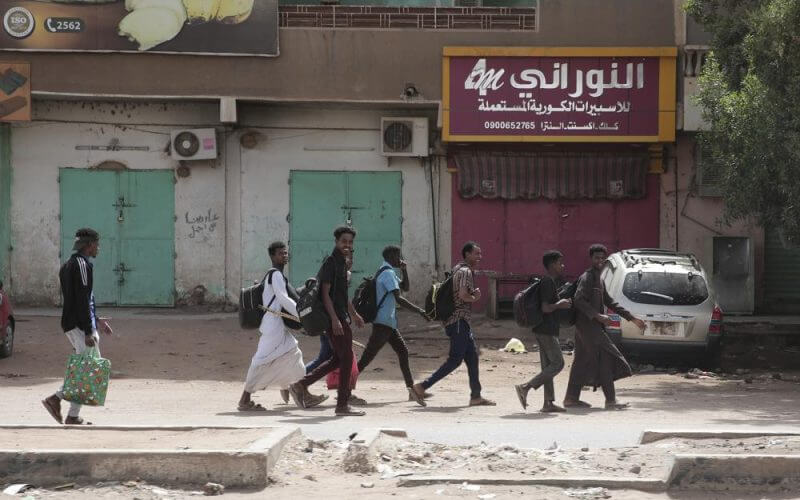 People walk past shuttered shops in Khartoum, Sudan, Monday, April 17, 2023. AP