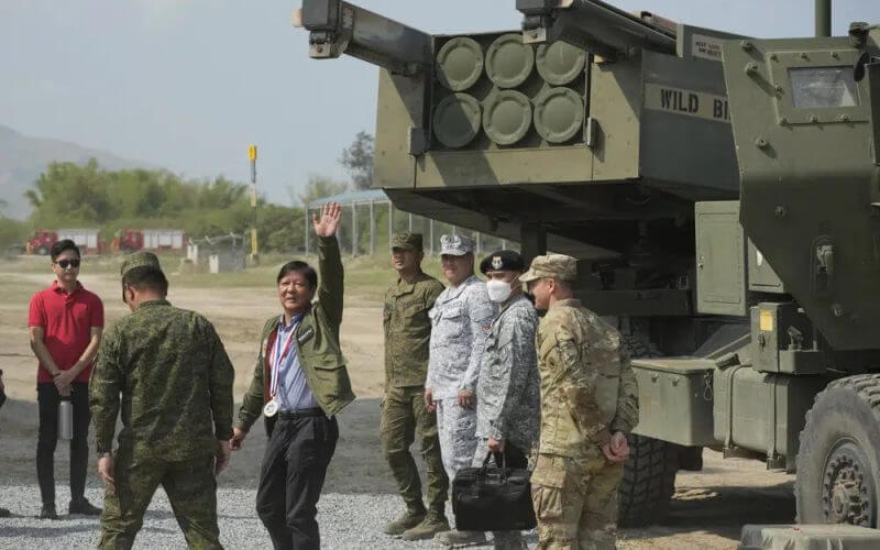 Philippine President Ferdinand Marcos Jr. waves beside a U.S. M142 High Mobility Artillery Rocket System (HIMARS) during a Combined Joint Littoral Live Fire Exercise at the joint military exercise called "Balikatan," Tagalog for shoulder-to-shoulder in a Naval station in Zambales province, northern Philippines on Wednesday, April 26, 2023. AP