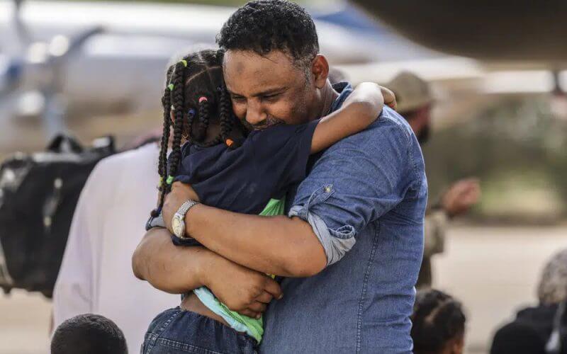 In this handout image provided by the UK Ministry of Defence, on Thursday, April 27, 2023, Violinist Othmano, right, hugs his daughter before boarding an RAF C-130, that will take them to Cyprus, at Wadi Seidna military airport, 22 kilometres (14 mi) north of Khartoum, Sudan. (PO Phot Aaron Hoare/UK Ministry of Defence via AP)