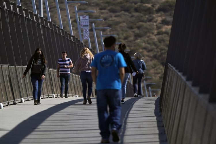 People walk on a bridge at the San Ysidro Port of Entry, connecting Tijuana, Mexico, to the United States. (AP Photo/Gregory Bull)