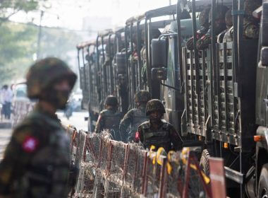 Soldiers stand next to military vehicles as people gather to protest against the military coup, in Yangon, Myanmar, February 15, 2021. REUTERS